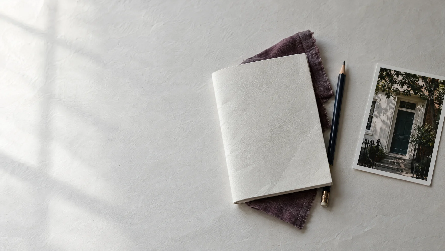 A linen-bound journal, pencil, and photographic print in quiet afternoon light